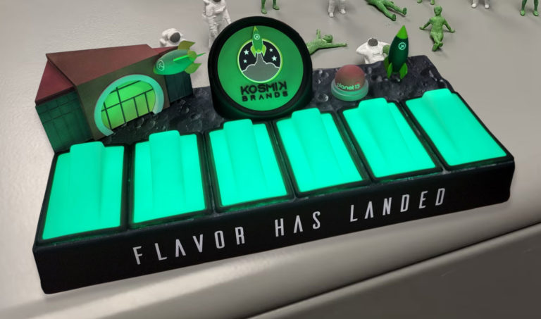 Kosmik Brands illuminated cannabis gummies display fabricated with neon green LED lighting and miniature space figures.