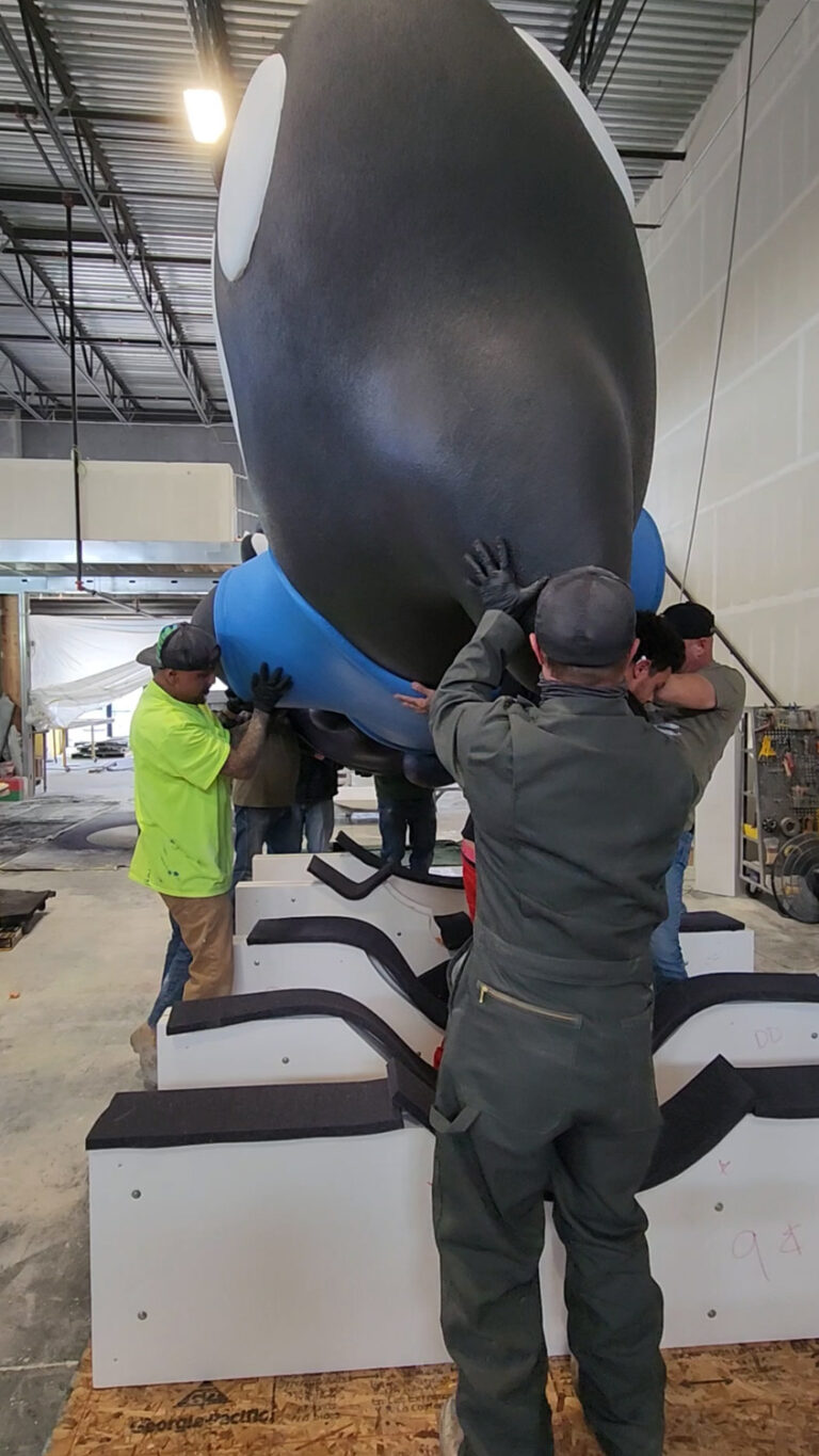 Giant Orca whale company mascot foam statue lifting onto wooden shipping crate