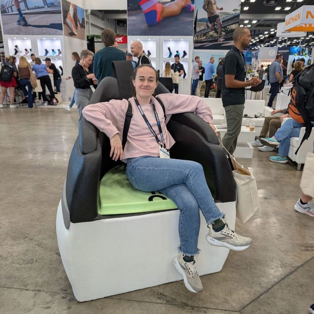 Attendee seated in a giant OOFOS shoe chair at a footwear trade show