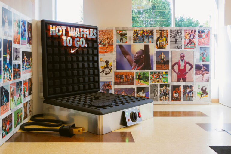 Giant waffle iron display with gridded plates, controls, and illuminated Nike graphics