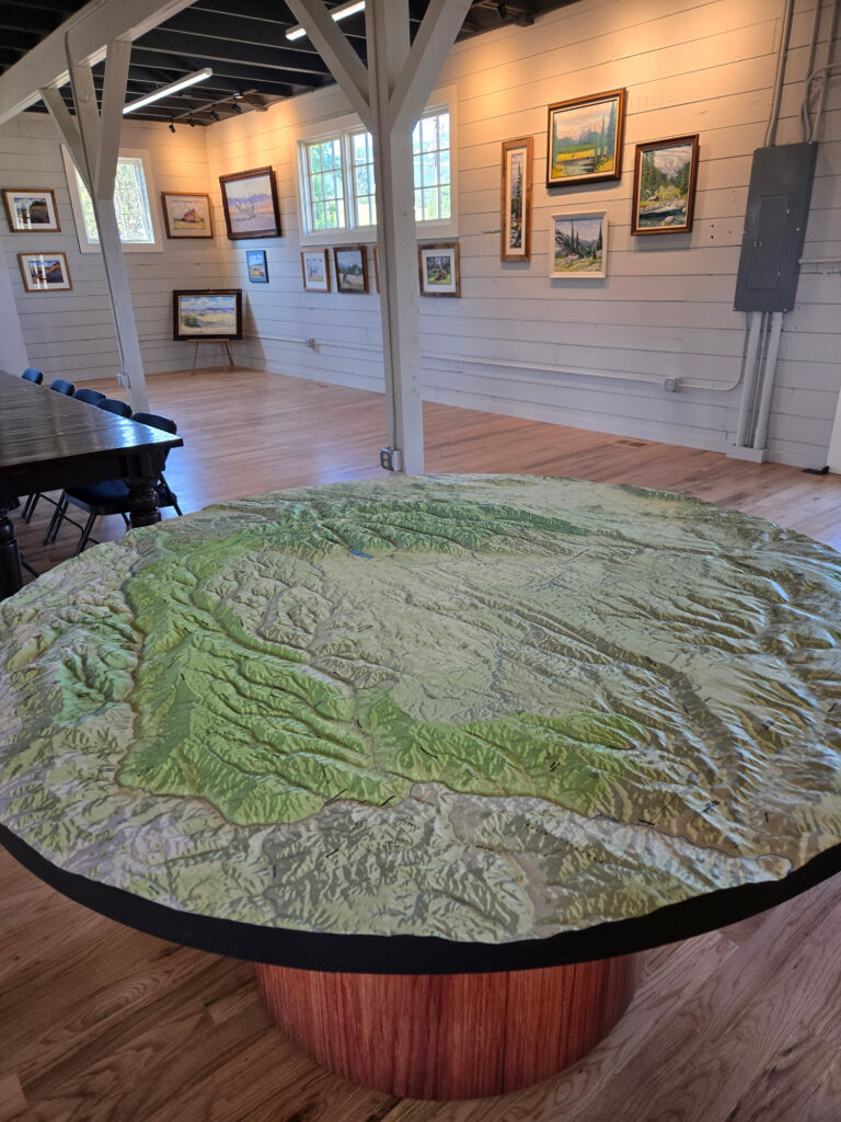 Custom 66-inch circular 3D raised relief topography map with a custom base, created for the Wallowa History Center in Wallowa, Oregon, highlighting a region of Wallowa County and surrounding parts of Oregon, Washington, and Idaho.