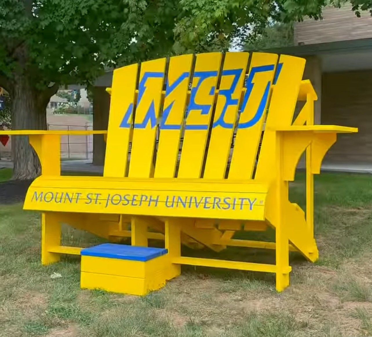 Giant yellow Adirondack chair with blue MSJ letters and Mount St. Joseph University wording