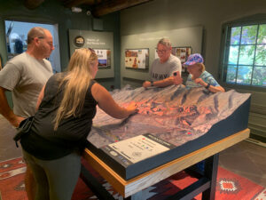 Interactive 3D park map concept for the Red Rocks Visitor Center Trading Post Building in Colorado, featuring trails, named rock formations, wildlife, geologic history.