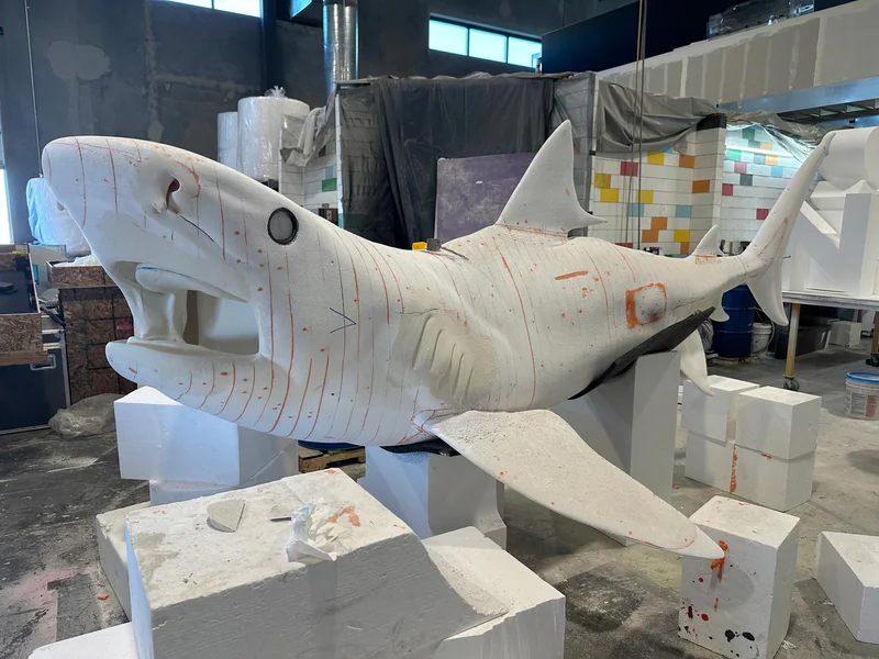 Foam shark sculpture being refined and detailed by hand.
